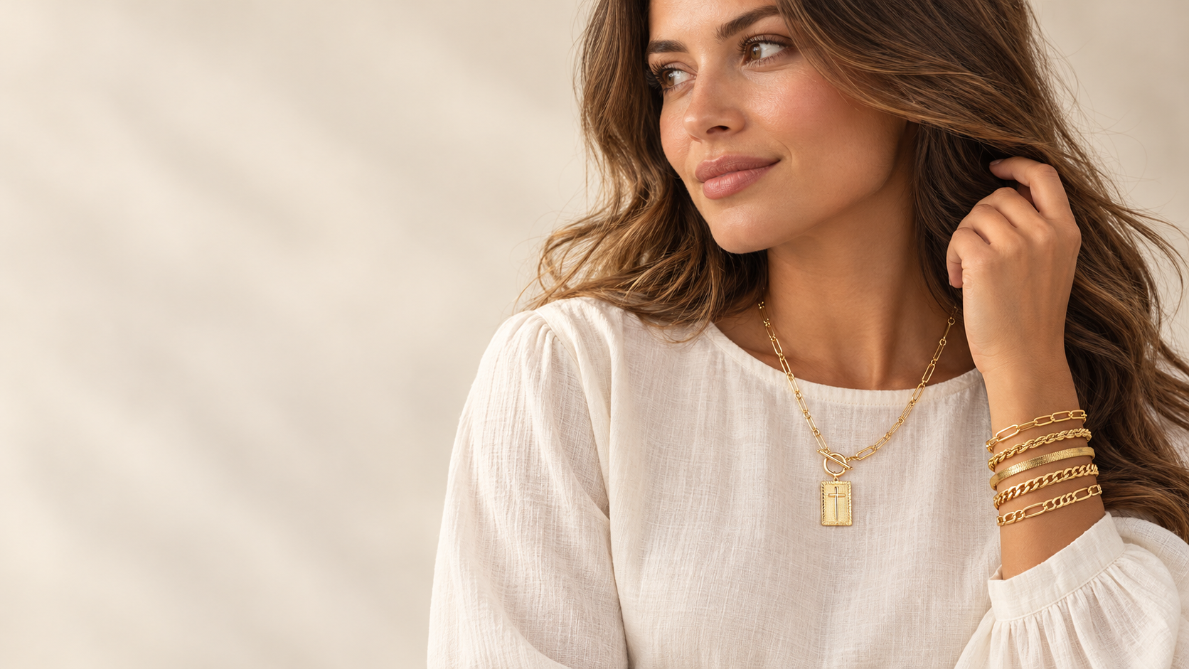 A model wearing the Vault Jewels cross necklace and five-chain bracelet stack